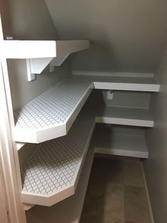 an empty pantry with white shelves and tile flooring on the bottom shelf is shown