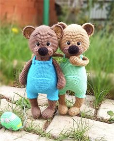 two crocheted teddy bears standing next to each other in front of a ball