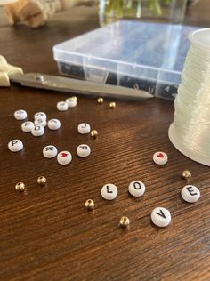 the spool of thread is next to some letters and beads on a wooden table