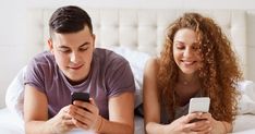 a man and woman laying in bed looking at their cell phones while they look at the screen