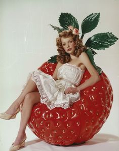 a woman sitting on top of a giant strawberry