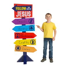 a young boy is standing next to a sign that says follow the path to jesus