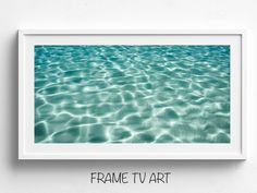 an art print with the words frame tv art in front of a white wall and blue water