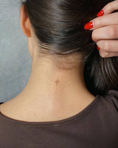 the back of a woman's head with a cross tattoo on her left neck