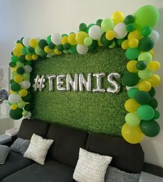 there is a couch with balloons on it and a tennis sign in the back ground