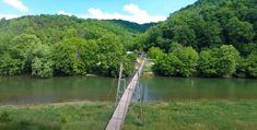 people walking across a suspension bridge over a river