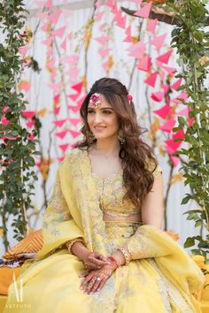 a woman in yellow dress sitting on a bench with pink and white decorations behind her