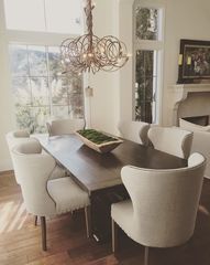 a dining room table with white chairs and a wooden centerpiece hanging from the ceiling