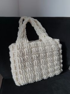 a white crocheted bag sitting on top of a black couch