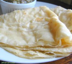 some tortillas on a white plate with a small bowl of salsa in the background