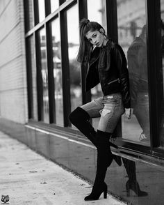 black and white photograph of a woman leaning on a window sill wearing high heel boots