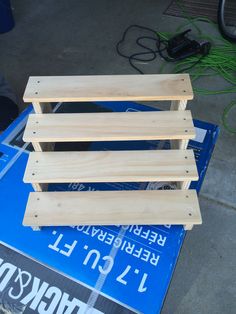 three pieces of plywood sitting on top of a blue box with wires in the background