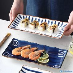 a person holding a plate with sushi and lemons on it next to another plate