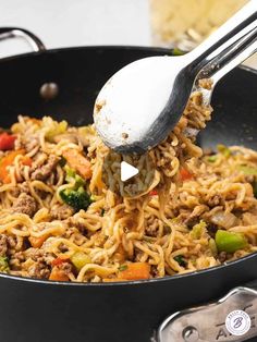 someone is stirring noodles in a skillet with a ladle to stir them together