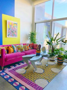 a living room filled with lots of colorful furniture and plants on top of rugs