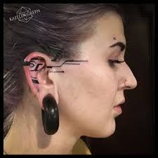 a woman with ear piercings on her face and behind her ear is an arrow