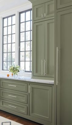 a kitchen with green cabinets and white counter tops