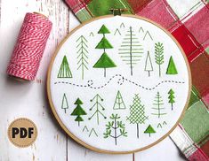 a cross stitch pattern with trees on it and some spools of thread next to it