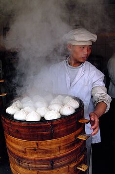 a man standing in front of a barrel filled with white food and steam coming out of it