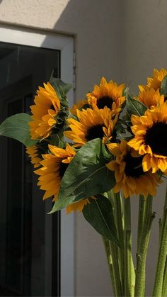 a vase filled with yellow sunflowers on top of a table