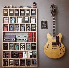 an electric guitar is sitting next to a shelf with many different types of pedals