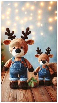 two crocheted deer dolls sitting next to each other on a wooden table with christmas lights in the background