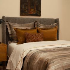 a bedroom with a bed, nightstand and painting on the wall above it's headboard