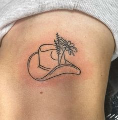 a woman's lower back tattoo with a hat and flowers