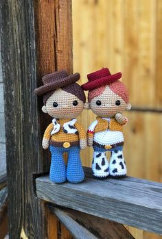 two crocheted toy figures are standing on a wooden ledge