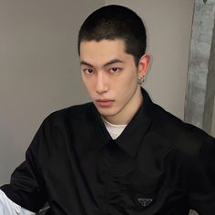 a young man wearing a black shirt and silver earrings