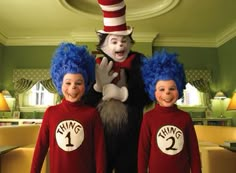 the cat in the hat is standing next to two children wearing red shirts and blue hair