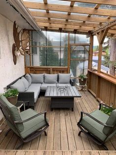 an outdoor living area with couches, tables and plants on the decking floor