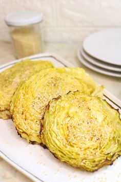 three pieces of artichoke on a white plate next to plates with sauces