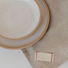 a white plate with red thread on it next to a napkin and a piece of cloth