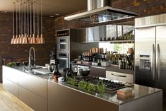 a modern kitchen with stainless steel appliances and hanging lights over the stove top ovens