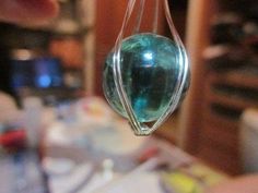 a green glass hanging from a hook in a room with other items on the table