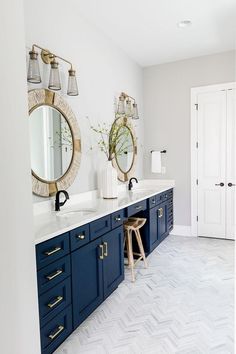 a bathroom with two mirrors and blue cabinets