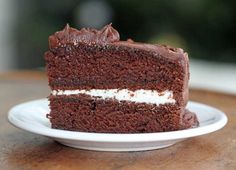 a piece of chocolate cake on a plate with white frosting and brown icing