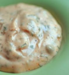 a green bowl filled with sauce on top of a table