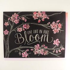 a chalkboard with pink flowers and the words live life in full bloom