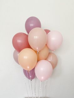 a vase filled with balloons on top of a wooden table next to a white wall