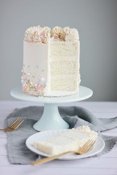 a white cake sitting on top of a table next to a slice of cake covered in frosting