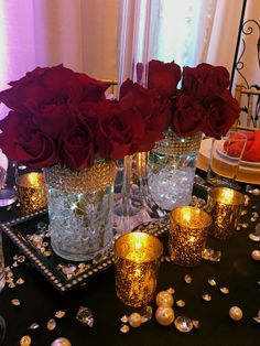 red roses are in vases on a table with candles and confetti around them