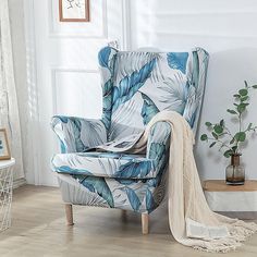 a blue and white chair sitting on top of a hard wood floor next to a potted plant