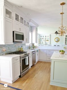 a kitchen with white cabinets and wood floors