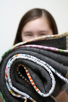 a woman holding up several pieces of fabric