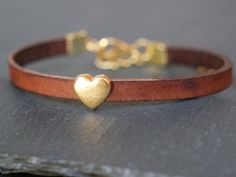 "A lovely dark brown leather bracelet with a small heart-shaped slider bead in gold. The bracelet is made from real leather which gives it a lovely rustic boho touch. As it is a natural material it can vary slightly in texture and colour and has a nice \"vintage effect\".  The metal findings are all gold plated. It is 5mm wide and 16-20cm long (adjustable with a chain extender) and can be made to your desired length. It comes lovingly packed in a handmade Origami envelope and an organza pouch. I can add a little handwritten personal note." Heart Bracelet Gold, Mandala Feather, Origami Envelope, Brown Leather Bracelet, Vintage Effect, Rustic Boho, Chain Extenders, Small Heart, Dark Brown Leather