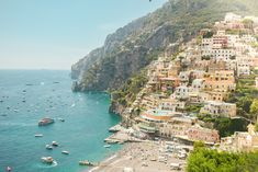 an aerial view of boats in the water and buildings on the cliff side, along with other boats