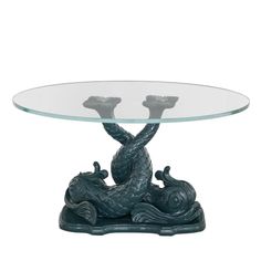 a glass and metal table with two candlesticks in the shape of a fish