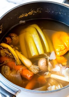 a pot full of soup with carrots, onions and other vegetables in the broth